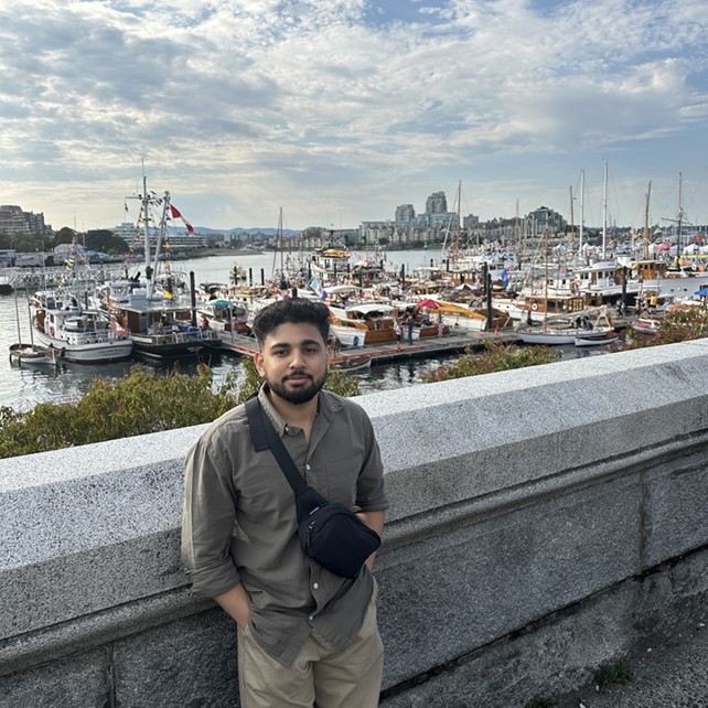 Ritesh Chopra, Content Specialist at Show and Tell Agency, standing in front of a harbour in Victoria, BC.